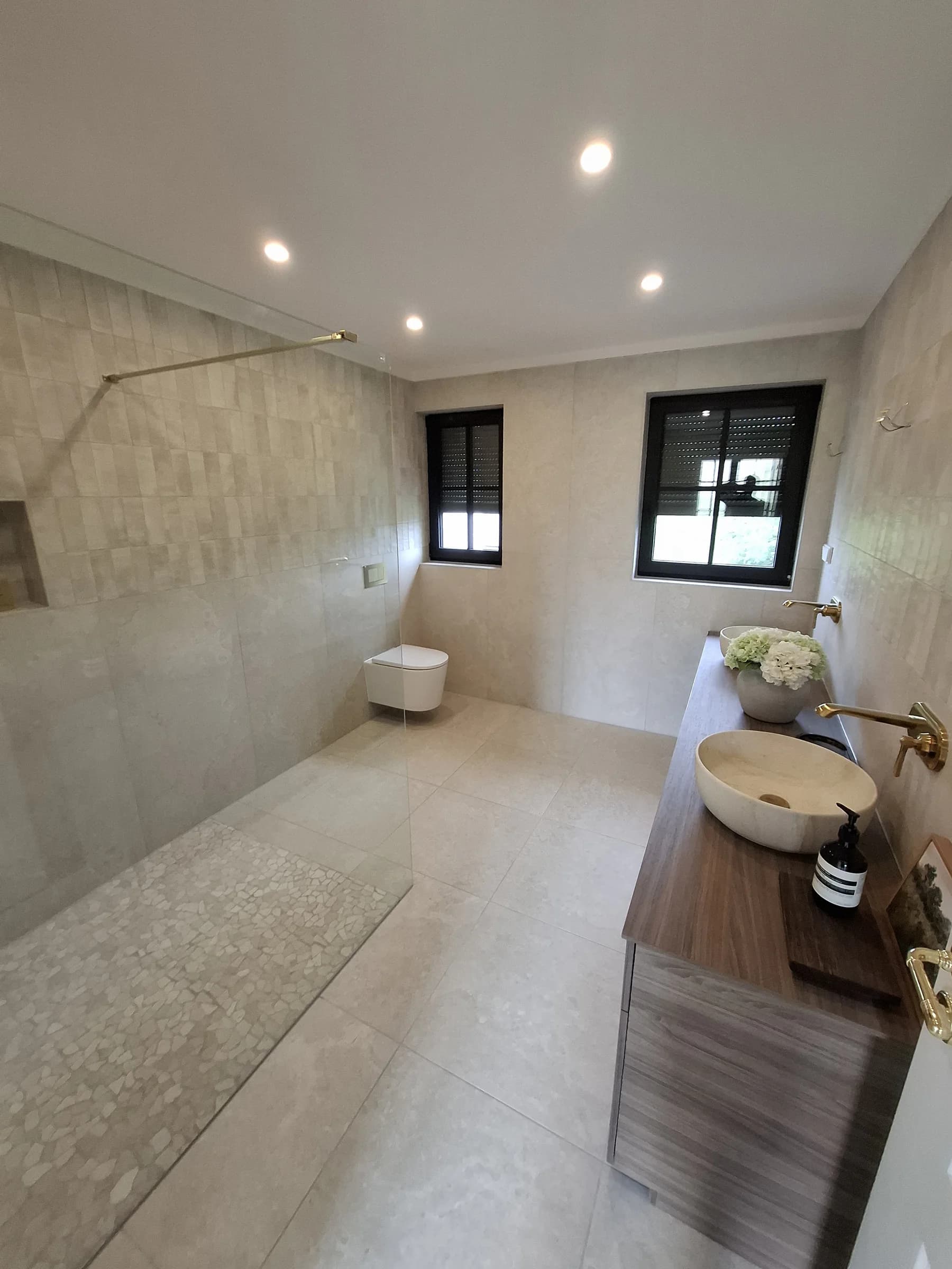 Blick durch das Bad mit Wand-WC, Aufsatzbecken auf Holzkonsole und Deckenspots