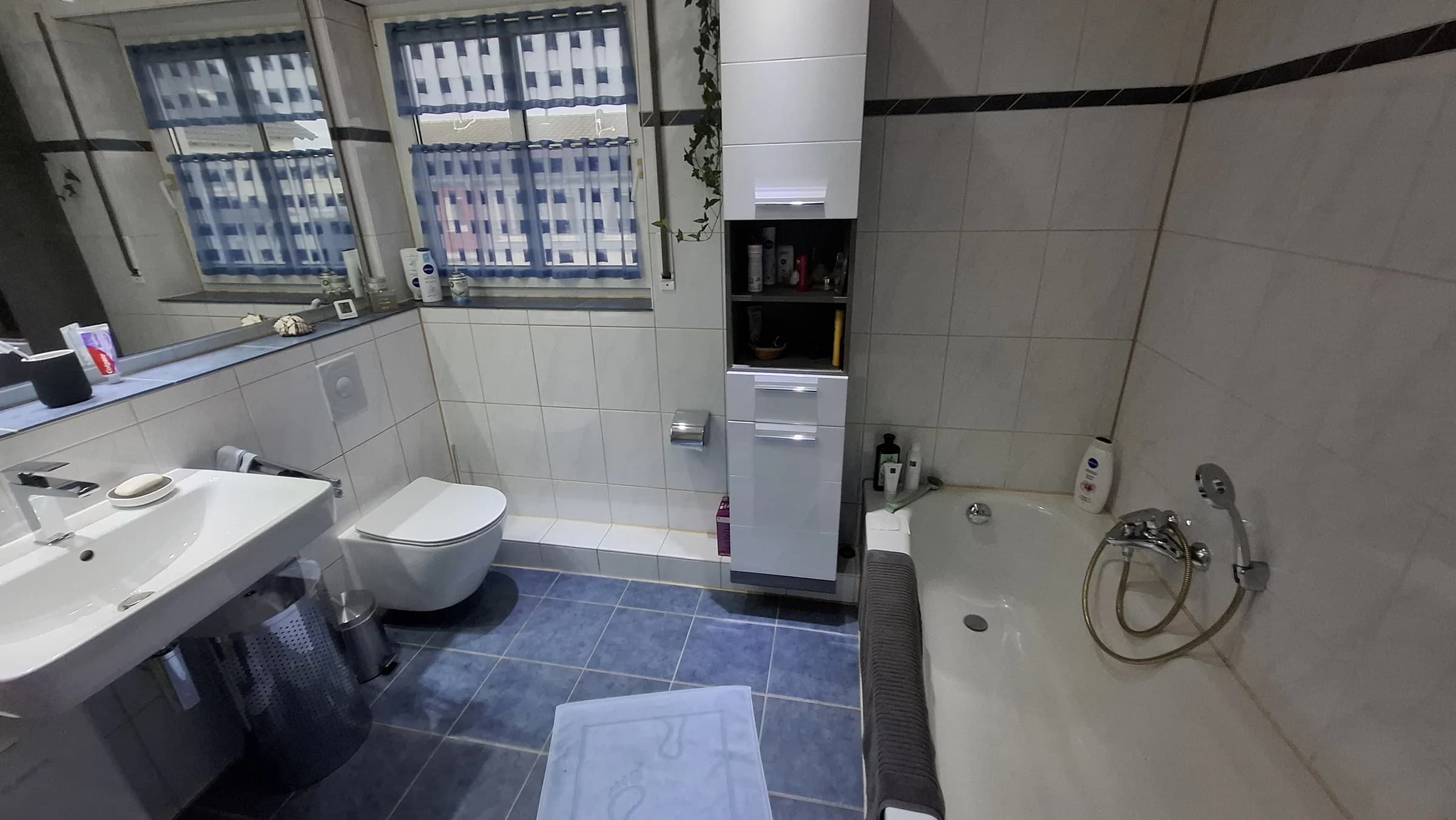 Altes Bad mit Badewanne, Wand-WC und kleinformatigen weißen Fliesen vor dem Umbau